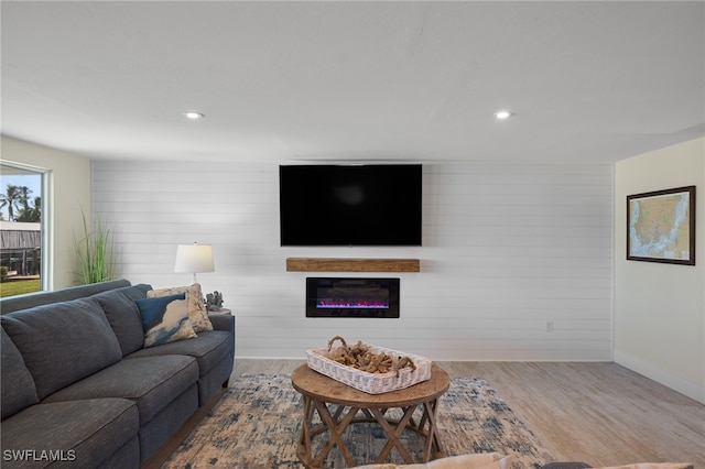 living room featuring hardwood / wood-style flooring, a fireplace, and wood walls