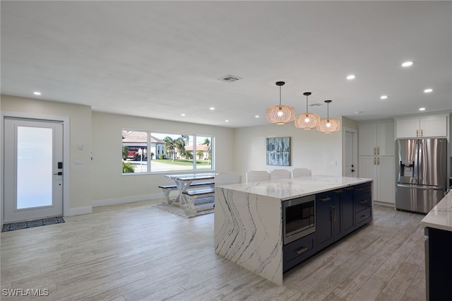 kitchen featuring a large island, appliances with stainless steel finishes, hanging light fixtures, light hardwood / wood-style floors, and white cabinets