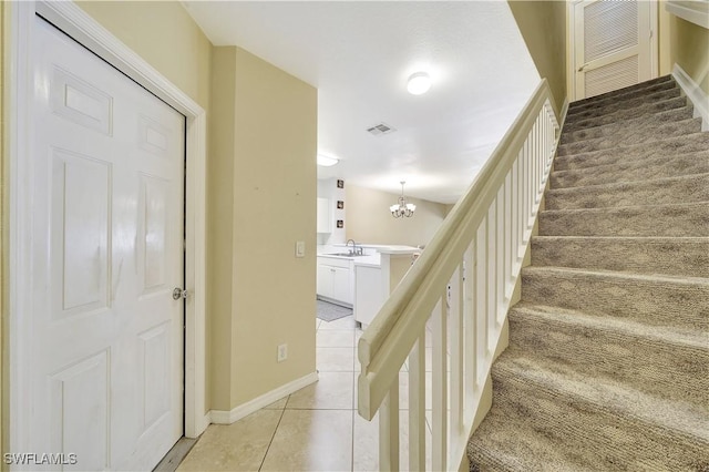 stairs featuring tile patterned floors, sink, and a chandelier