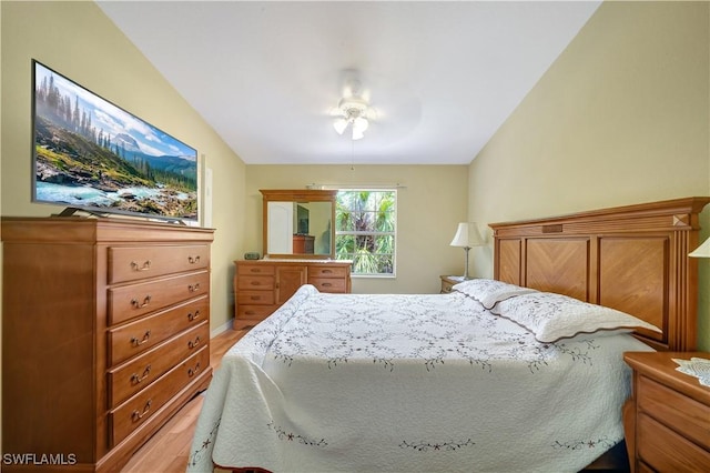 bedroom with ceiling fan, light hardwood / wood-style floors, and vaulted ceiling