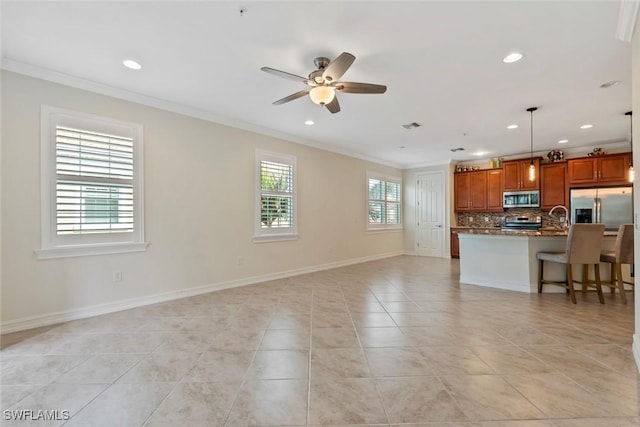 kitchen with a kitchen breakfast bar, ornamental molding, stainless steel appliances, decorative light fixtures, and a center island with sink