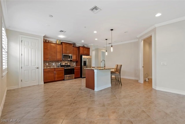 kitchen featuring a kitchen island with sink, hanging light fixtures, stainless steel appliances, a kitchen breakfast bar, and decorative backsplash