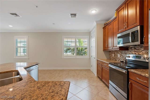 kitchen featuring a healthy amount of sunlight, light tile patterned floors, ornamental molding, and appliances with stainless steel finishes