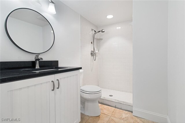 bathroom with tiled shower, tile patterned floors, vanity, and toilet