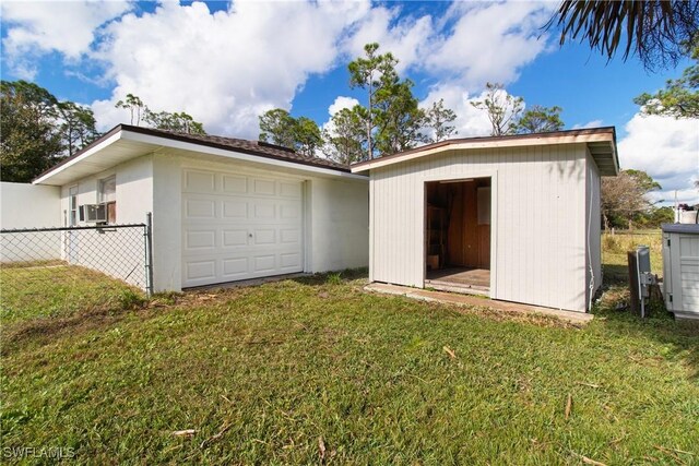 back of house featuring a lawn, cooling unit, and an outbuilding