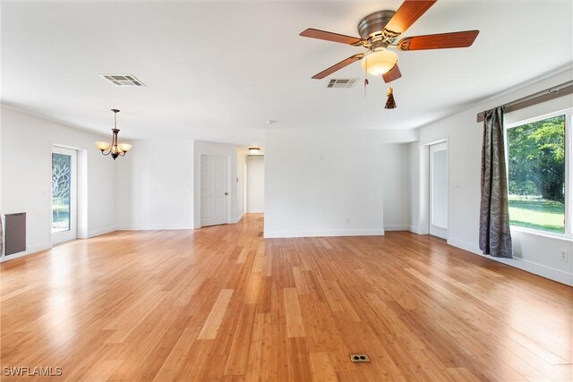 unfurnished living room with ceiling fan with notable chandelier and light wood-type flooring