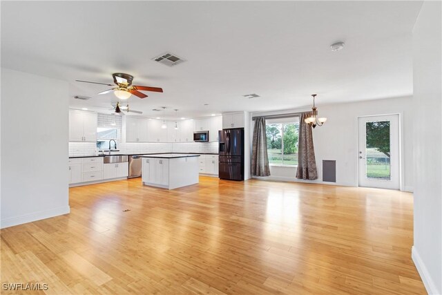 unfurnished living room with sink, ceiling fan with notable chandelier, and light wood-type flooring