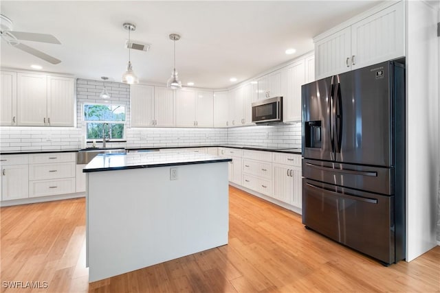 kitchen with backsplash, white cabinets, ceiling fan, appliances with stainless steel finishes, and decorative light fixtures