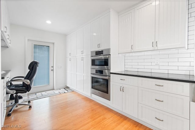 kitchen with light hardwood / wood-style flooring, white cabinets, and stainless steel double oven