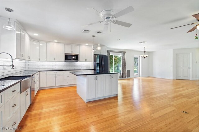 kitchen with white cabinets, stainless steel appliances, hanging light fixtures, and sink