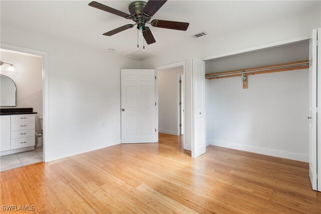 unfurnished bedroom featuring light wood-type flooring, ensuite bathroom, a closet, and ceiling fan