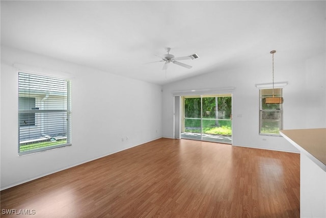 empty room with ceiling fan, hardwood / wood-style floors, a healthy amount of sunlight, and lofted ceiling