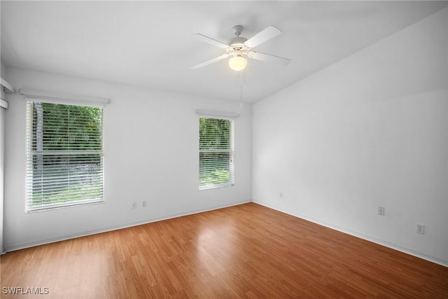 spare room featuring ceiling fan, a healthy amount of sunlight, and hardwood / wood-style flooring