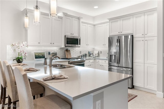 kitchen featuring kitchen peninsula, a breakfast bar area, stainless steel appliances, pendant lighting, and white cabinets