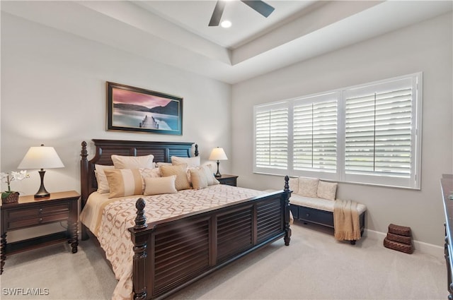 carpeted bedroom with ceiling fan and a tray ceiling