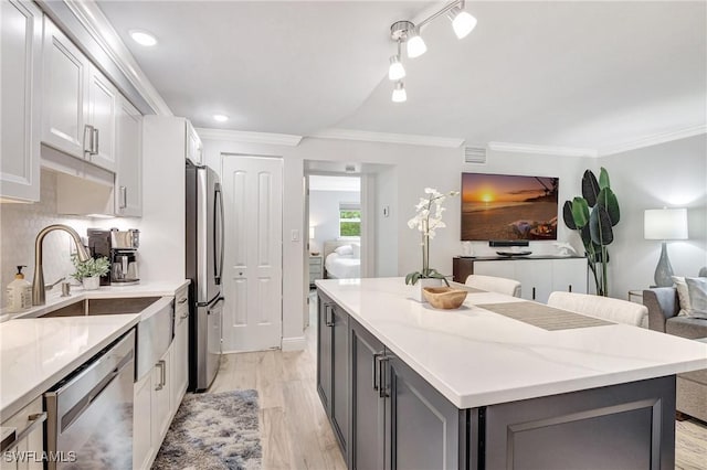 kitchen featuring light hardwood / wood-style flooring, a kitchen island, stainless steel appliances, light stone countertops, and white cabinets