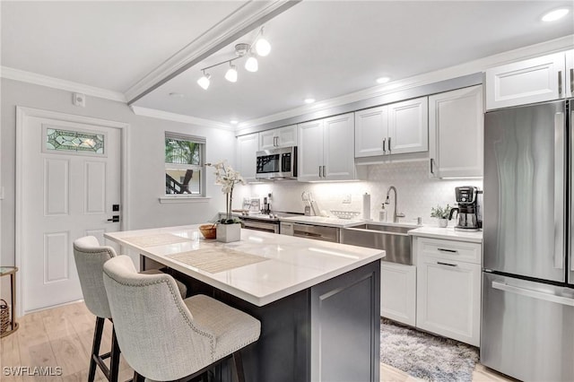 kitchen featuring white cabinetry, crown molding, stainless steel appliances, and a center island