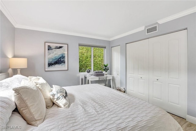 bedroom with multiple closets, crown molding, and light hardwood / wood-style floors