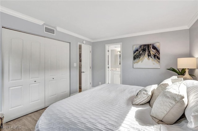 bedroom with ornamental molding, connected bathroom, a closet, and light hardwood / wood-style flooring