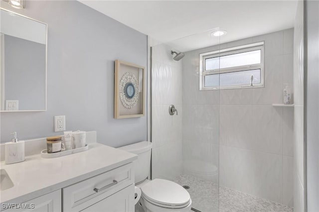 bathroom featuring vanity, toilet, and tiled shower