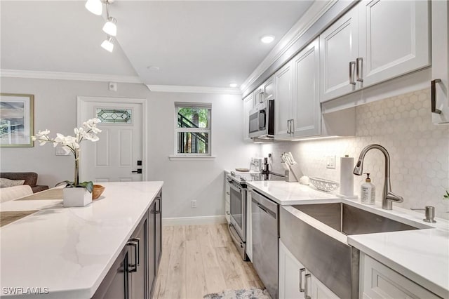 kitchen with stainless steel appliances, ornamental molding, light stone countertops, and light hardwood / wood-style flooring