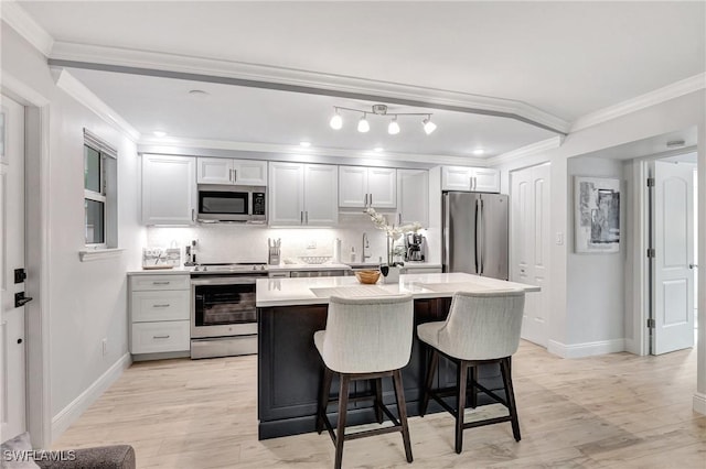 kitchen with a kitchen island, sink, a breakfast bar area, stainless steel appliances, and crown molding