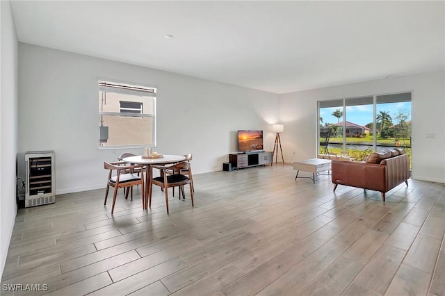 dining room with wine cooler, plenty of natural light, and light hardwood / wood-style flooring