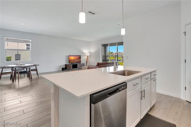 kitchen featuring a kitchen island with sink, sink, pendant lighting, and stainless steel dishwasher