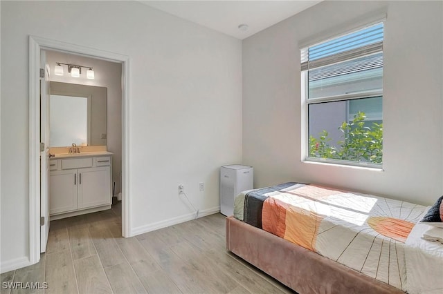 bedroom with ensuite bathroom, sink, and light wood-type flooring