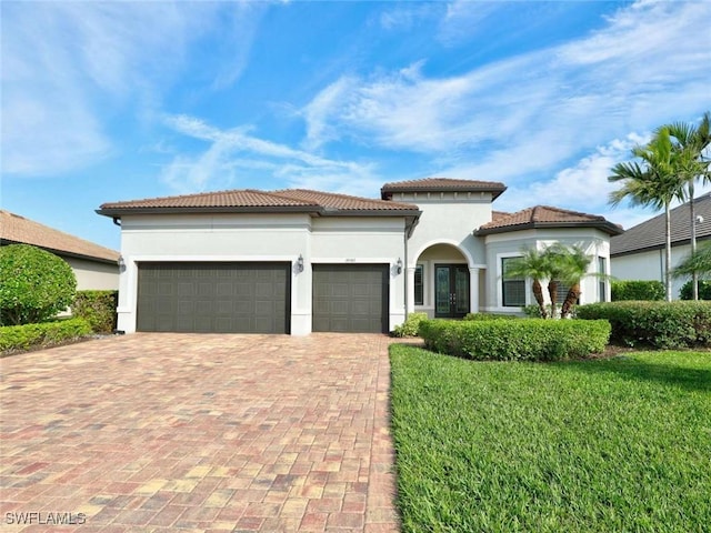 mediterranean / spanish home featuring a garage and a front yard