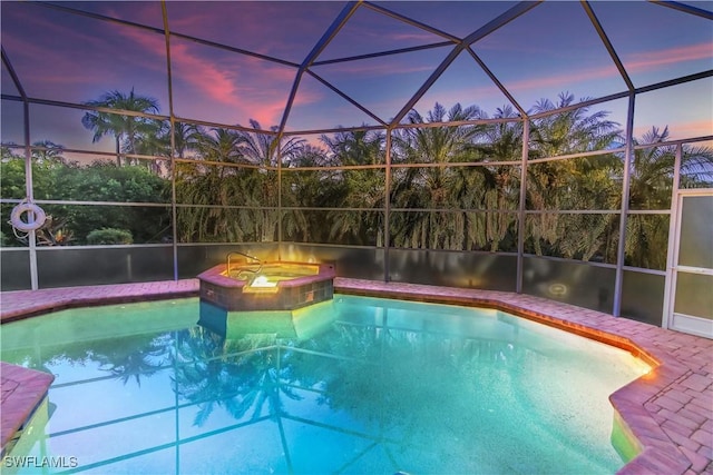 pool at dusk with a lanai and an in ground hot tub