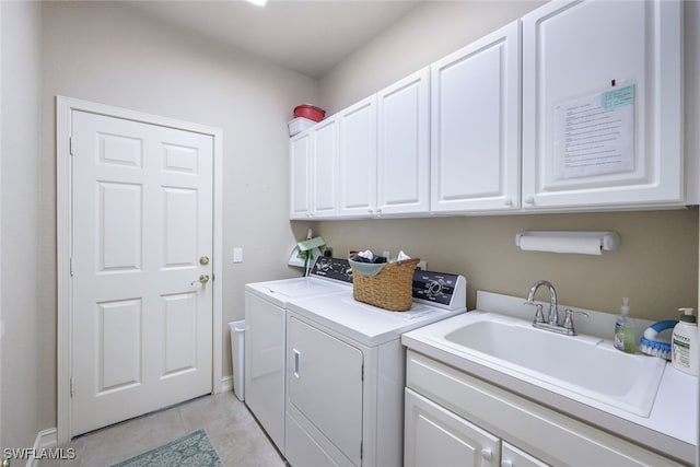 clothes washing area featuring washer and clothes dryer, light tile patterned floors, cabinets, and sink