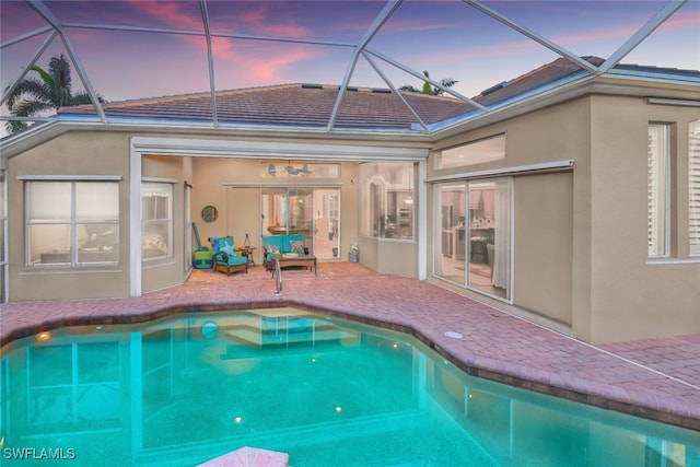 pool at dusk featuring a patio area and a lanai