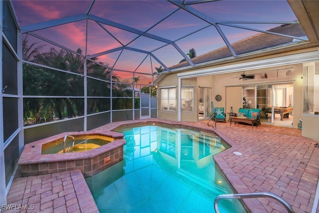 pool at dusk with outdoor lounge area, ceiling fan, a lanai, a patio area, and an in ground hot tub