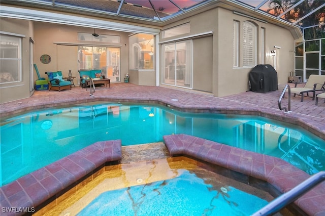 view of pool featuring ceiling fan, a patio area, glass enclosure, and grilling area