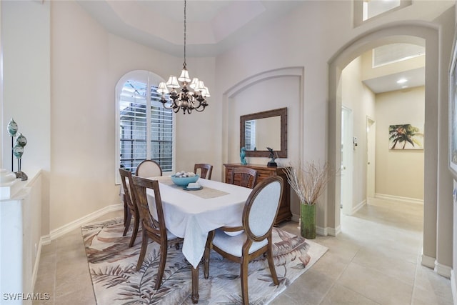 tiled dining area with a towering ceiling and an inviting chandelier