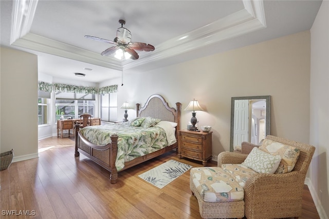 bedroom with a tray ceiling, ceiling fan, ornamental molding, and hardwood / wood-style flooring