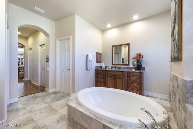 bathroom featuring vanity and tiled bath