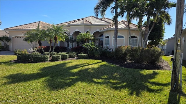 mediterranean / spanish home with a garage and a front lawn