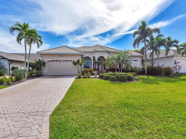 mediterranean / spanish house featuring a garage, a tile roof, decorative driveway, a front lawn, and stucco siding