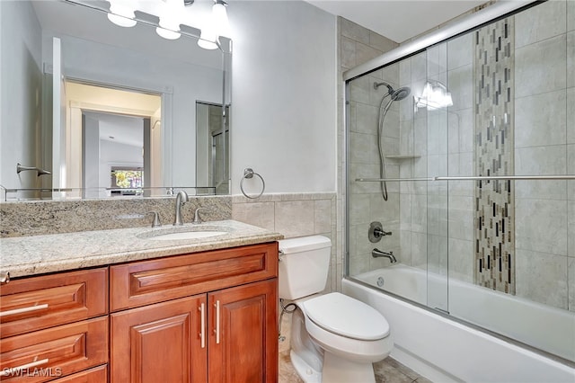 full bathroom featuring tile patterned floors, vanity, tile walls, enclosed tub / shower combo, and toilet