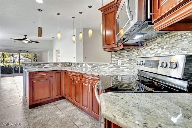 kitchen with kitchen peninsula, appliances with stainless steel finishes, light stone countertops, tasteful backsplash, and decorative light fixtures