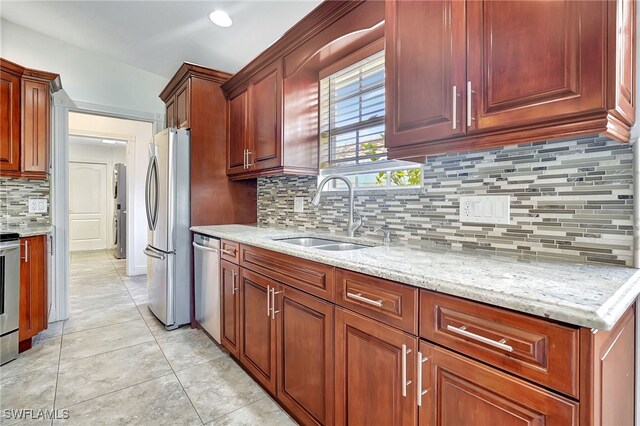 kitchen with light stone countertops, sink, backsplash, light tile patterned flooring, and appliances with stainless steel finishes