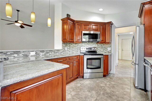 kitchen with light stone countertops, ceiling fan, hanging light fixtures, stainless steel appliances, and tasteful backsplash