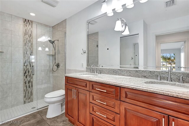 bathroom with tile patterned floors, a shower with door, vanity, and toilet