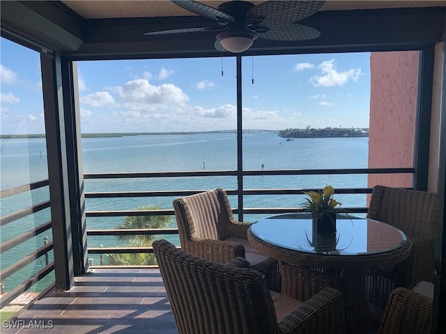 sunroom featuring ceiling fan and a water view