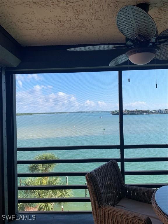 balcony featuring ceiling fan and a water view