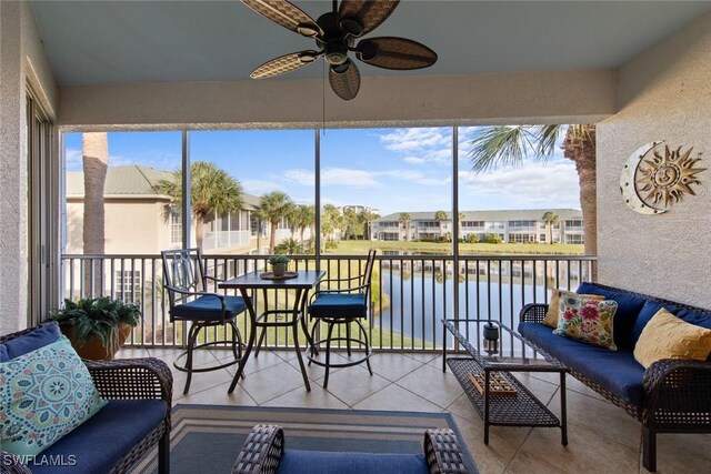 sunroom featuring ceiling fan and a water view