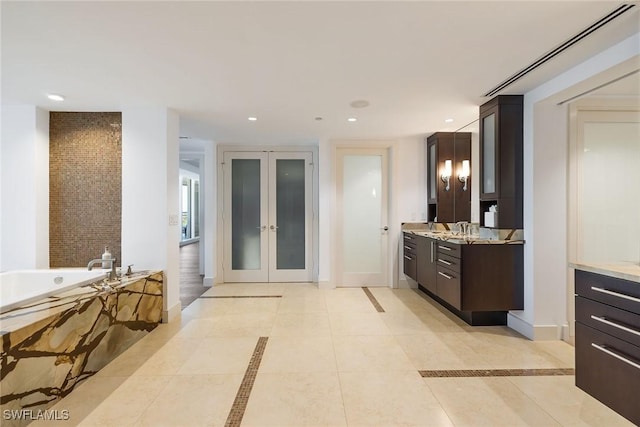 bathroom featuring tile patterned flooring, vanity, french doors, and tiled tub