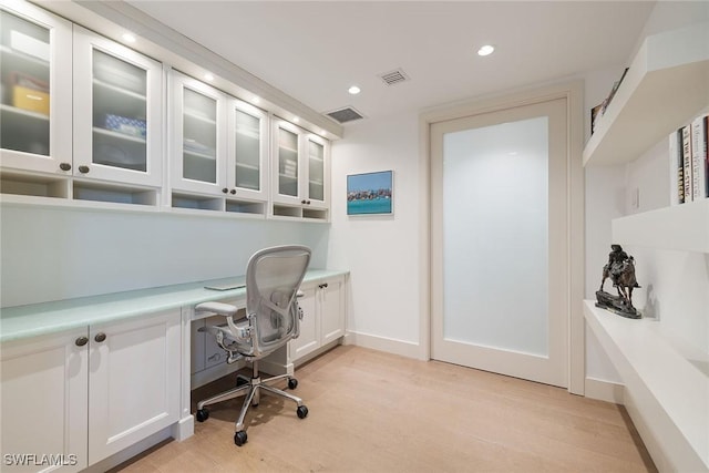 office space with built in desk and light hardwood / wood-style floors